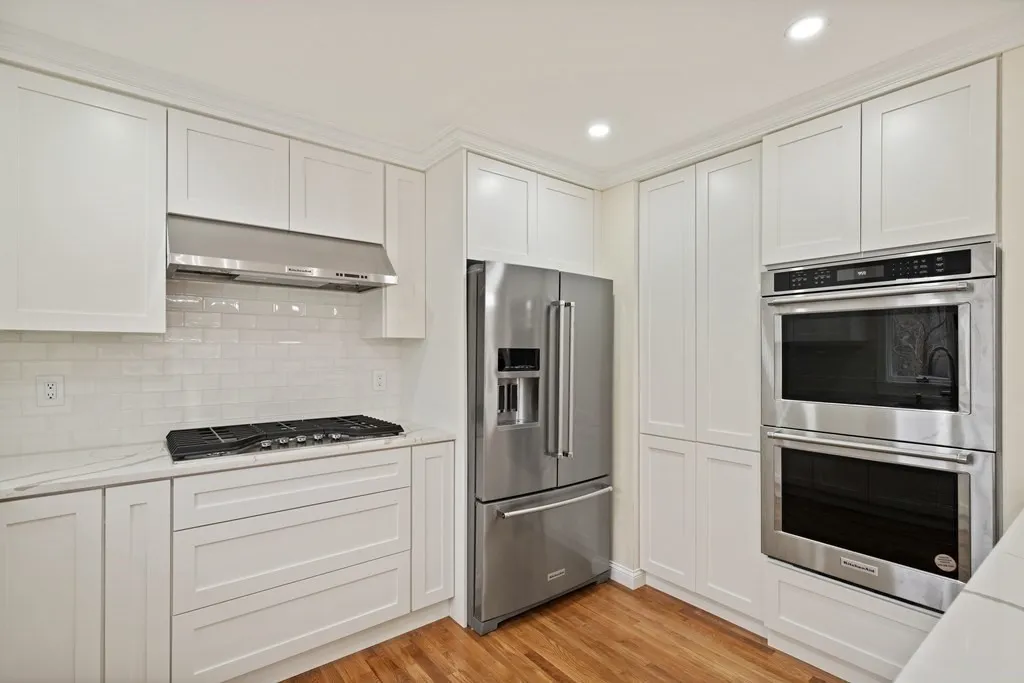White cabinets, refrigerator, and wall ovens in the Amesbury kitchen