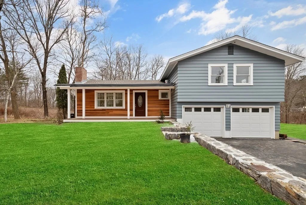 Gray custom home with a wood porch and two-car garage in Amesbury, Massachusetts