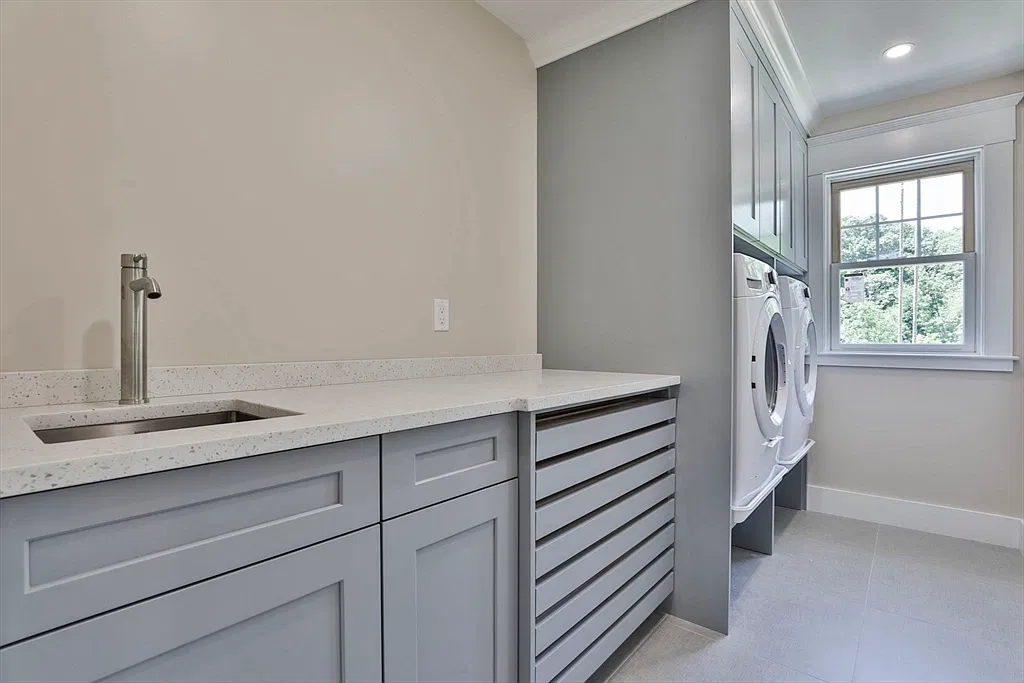 Laundry room with gray cabinets in the Amesbury home