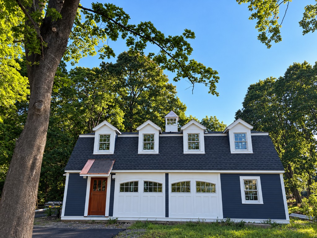 Blue carriage house with dormers and white garage doors in Newburyport, Massachusetts